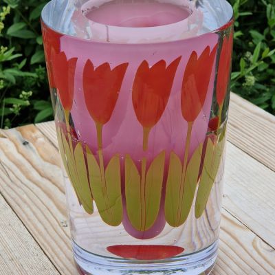 Vas med tulpaner  Lioba Maria Solga  Tulpaner växer i en trädgård och behöver en vas när de plockas. När de har vissnat finns det fortfarande ett minne av blomsterprakten kvar.